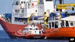 An Italian Coast Guard boat approaches the French NGO "SOS Mediterranee" Aquarius ship as migrants are being transferred, in the Mediterranean Sea, June 12, 2018. 