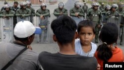 People waiting to cross to Venezuela stand opposite Venezuelan National guards at the border between Venezuela and Brazil in Pacaraima, Roraima state, Brazil, Feb. 22, 2019. 