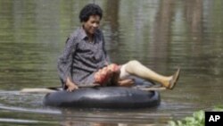 ស្រ្តី​ខ្មែរ​ម្នាក់​ជិះ​លើ​កង់​រថយន្ត នៅ​លើ​ទឹកជំនន់​ ដែល​ជន់​លើ​ផ្លូវ​មួយ​ក្នុង​ខេត្ត​កំពង់ធំ ដែល​ស្ថិត​នៅ​ចម្ងាយ​ប្រមាណ ១២០ គ.ម ភាគ​ខាង​ជើង​រាជធានី​ភ្នំពេញ។ 