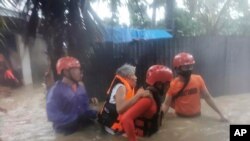In this photo provided by the Philippine Coast Guard, rescuers evacuate residents to safer ground as floods caused by Tropical Storm Choi-wan hit Maasin City in Southern Leyte province, central Philippines, June 1, 2021. 
