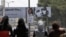 Palestinian girls walk near a billboard with a picture of US President Barack Obama, in the West Bank city of Ramallah.