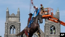 Crews attach straps to the statue of Confederate General J.E.B. Stuart on Monument Avenue in Richmond, Va., July 7, 2020.