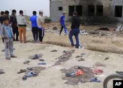 People inspect the aftermath of a suicide bombing at a soccer field in Iskandariya, 25 miles (about 40 kilometers) south of Baghdad, Iraq, March 26, 2016.