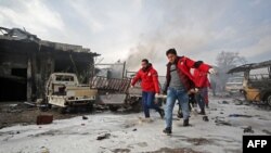 FILE - Syrian paramedics carry away on a stretcher a wounded man following a regime air strike on a vegetable market in Syria's last major opposition bastion of Idlib, Jan. 15, 2020. 