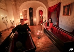 These two fans of vampire folklore pose in coffins at Dracula's Castle in Romania, 2016.
