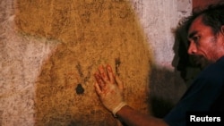 Seorang petugas rumah pemakaman, yang tangannya terkena darah orang-orang yang dibunuh dalam perang narkoba, bersandar di sebuah rumah di Manila, Filipina, November 2016.