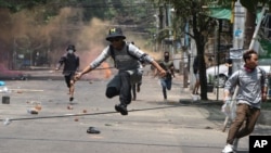 Anti-coup protesters run to avoid military forces during a demonstration in Yangon, Myanmar, March 31, 2021.