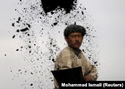 Seorang buruh tambang batubara membongkar muatan batubara dari truk ke tempat penimbunan di Kabul, Afghanistan,19 November 2015. (Foto:Reuters).