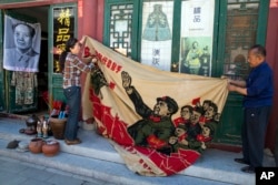 北京旧货市场上的1969年的文革横幅画布，上面有戴红卫兵袖章的毛泽东、江青和红卫兵。横幅上写着“大海航行靠舵手” 和“毛主席检阅文化革命大军”（2016年5月16日）