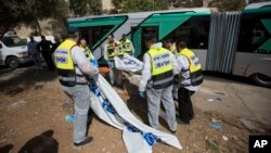 Petugas Israel mengangkut korban serangan di sebuah bus di Yerusalem, Selasa (13/10).