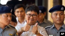 Reuters journalist Wa Lone, center, gives a thumbs up sign as he is escorted by police upon arrival at the court for trial in Yangon, Myanmar Friday, April 20, 2018. 