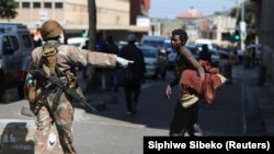Un militaire sud-africain s'adresse à un sans-abri lors du premier jour d'un confinement national de 21 jours pour tenter de contenir l'épidémie de coronavirus, à Johannesburg, Afrique du Sud, le 27 mars 2020. (Photo: Siphiwe Sibeko/Reuters)