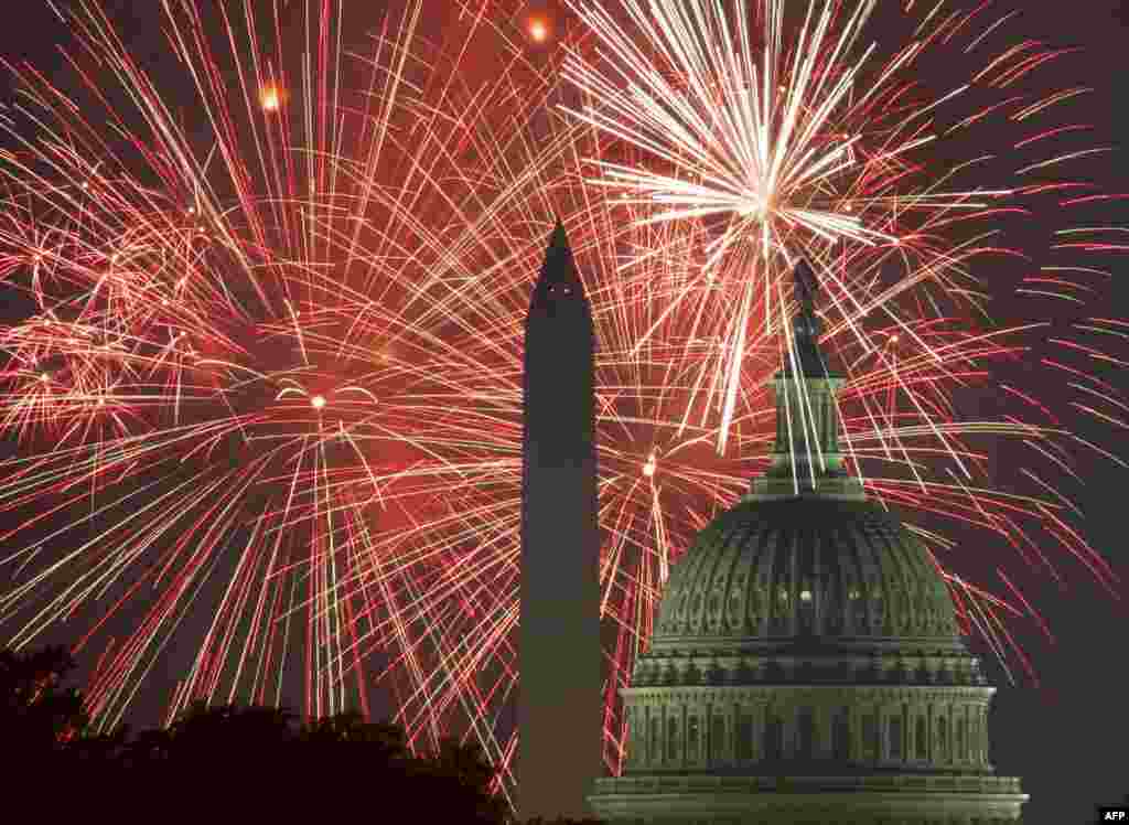 美国国庆节，首都华盛顿，礼花照亮夜空，辉映着国会大厦和华盛顿纪念碑 （2017年7月4日）。