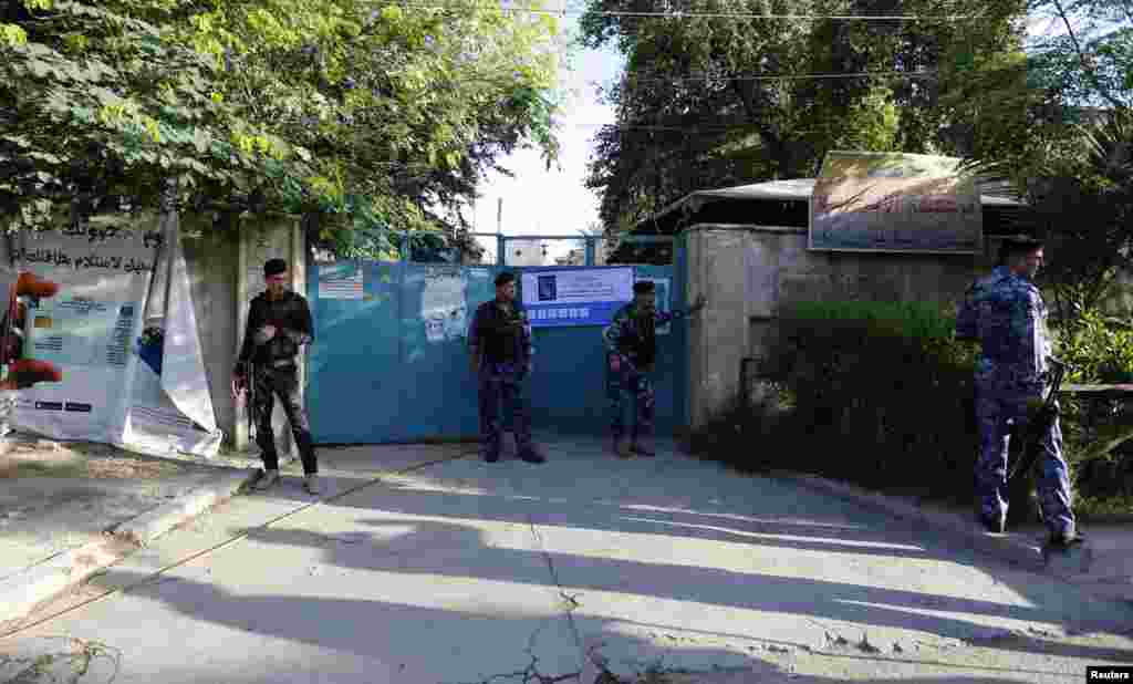 Iraqi policemen stand guard near a polling station, Baghdad, April 30, 2014.