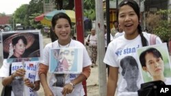 In this Nov. 12, 2010 photo, supporters of Myanmar's pro-democracy leader Aung San Suu Kyi hold portraits of their detained leader outside her National League for Democracy party in Rangoon, Burma.