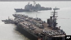 FILE - U.S. aircraft carrier USS Ronald Reagan anchors as U.S. Aegis Ship passes after they arrive at Busan port for joint military exercises in Busan, South Korea. The United States and South Korea started joint naval exercises, Nov. 11, 2017, that will involve three U.S. aircraft carriers in what military officials describe as a clear warning to North Korea.