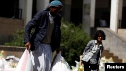 A man carries sacks of wheat flour he received from a local charity during the holy month of Ramadan in Sanaa, Yemen, May 29, 2017. 