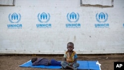 Seorang anak pengungsi asal Sudan Selatan duduk di atas terpal di luar tenda pengungsi di pusat penampungan Impevi di utara Uganda, pada 9 Juni 2017. (Foto: AP/Ben Curtis)
