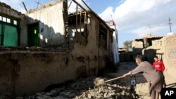 Warga Afghanistan membersihkan reruntuhan bangunan pasca gempa di ibukota Kabul, Senin (26/10).