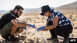 Ahli biologi Chili Cristiana Dorador dan Jonathan Garcia mencari sampel batuan untuk menganalisisnya di Yungay, Gurun Atacama, sekitar 80 kilometer selatan Antofagasta, Chili pada 7 Maret 2017, sebagai ilustrasi. (Foto: AFP)