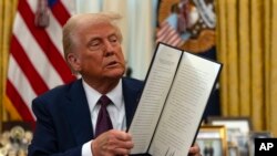 Претседателот Доналд Трамп држи потпишана извршна наредба во Овалната канцеларија во Белата куќа, во Вашингтон, 23 јануари 2025 година