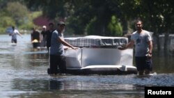 Orang-orang menggunakan kasur yang berisi udara untuk membuat harta miliknya tidak tenggelam di kawasan yang dilanda banjir di Port Arthur, Texas, 31 Agustus 2017 (foto: REUTERS/Carlo Allegri)
