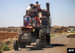 A Syrian family rides with belongings on a tractor-drawn trailer as they flee from fighting in the southern Syrian province of Daraa, June 21, 2018.