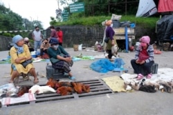Naga women, wearing face masks as a precaution against the coronavirus, sit by the side of a road selling poultry on the eve of International Day of the World's Indigenous Peoples, in Kohima, India, Aug. 8, 2020.