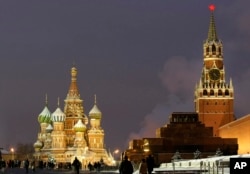 FILE - People walk in Red Square, with St. Basil Cathedral (left) the Kremlin's Spassky Tower (right rear) and Lenin Mausoleum (right) in Moscow.
