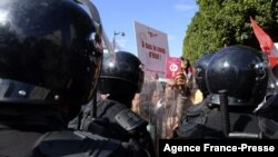FILE - Protesters confront riot police during an anti-government rally along Habib Bourguiba avenue in Tunisia's capital Tunis, Oct. 10, 2021.