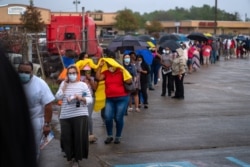 Orang-orang berbaris untuk memberikan suara mereka untuk pemilihan presiden yang akan datang karena pemungutan suara ketika badai tropis Zeta mendekati Pantai Teluk di New Orleans, Louisiana, AS, 27 Oktober 2020. (Foto: REUTERS/Kathleen Flynn)