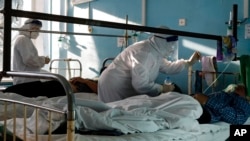 Petugas medis yang menggunak pakaian hazmat untuk melindungi diri dari infeksi COVID-19 memeriksa pasien ruangan perawatan intensif di sebuah rumah sakit di Volgograd, Russia, pada 21 November 2021. (Foto: AP/Alexandr Kulikov)