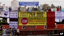 FILE - Cambodian non-governmental organization (NGOs) activists shout slogans during a protest against a proposed Don Sahong dam, in a tourist boat along the Tonle Sap river, in Phnom Penh, Cambodia, Thursday, Sept. 11, 2014.