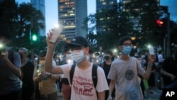 Pro-democracy demonstrators march holding their phones with flashlights on during a protest to mark the first anniversary of a mass rally against the now-withdrawn extradition bill in Hong Kong, Tuesday, June 9, 2020. One year ago, a sea of humanity…