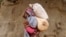 A displaced Somali woman carries a child and her belongings as she arrives at a temporary dwelling after fleeing famine in the Marka Lower Shebbele regions to the capital Mogadishu, Sept. 20, 2014. 