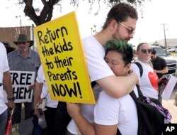 FILE - In this June 25 photo, 2018, Diana Jung Kim, right, and Homer Carroll, both from Houston, hug during a protest outside the U.S. Border Patrol Central Processing Center in McAllen, Texas.