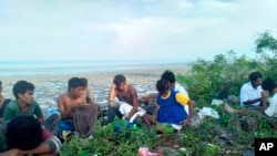 Wasu jama'a da ke kyautata zaton 'yan kabilar Rohingya ne yayin da wani kwalekwale ya sauke su a gabar ruwan kasar Malaysia
