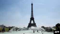 FILE - People cool themselves at the Trocadero Fountain in front of The Eiffel Tower in Paris on July 27, 2018, as a heatwave continues across northern Europe.