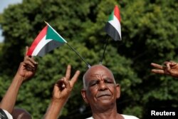 Protesters make victory signs as one of them carry Sudanese flags on his head during a demonstration in front of the Defence Ministry in Khartoum, Sudan, April 18, 2019.