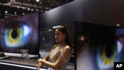 Seorang model berdiri di samping layar lebar Samsung di sebuah pameran internasional di Shanghai, 6 November 2018.