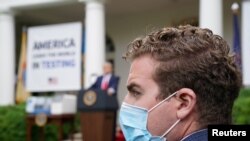 A Trump administration staffer wears a protective face mask in the Rose Garden as U.S. President Donald Trump holds a coronavirus disease (COVID-19) outbreak response briefing at the White House in Washington, May 11, 2020.