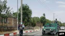 FILE - Afghan policemen stand guard at the gate of one of Kabul's universities, June 4, 2018.