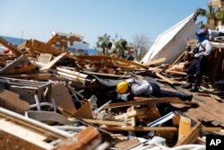 A member of a South Florida urban search and rescue team sifts through a debris pile for survivors of hurricane Michael in Mexico Beach, Fla., Oct. 14, 2018.