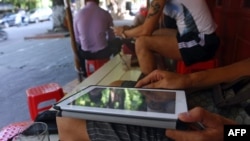 FILE - A customer uses his tablet to access the Internet at a 'wifi coffee shop' in downtown Hanoi.