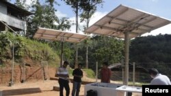 Sekelompok pekerja memasang panel tenaga surya untuk menggerakkan menara Indosat di Mambi, Sulawesi Barat. (Reuters/Indosat)