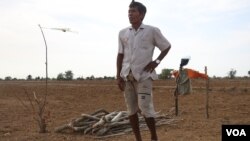 លោក មិត្ត ឈឿ អាយុ៦៥ឆ្នាំ ឈរ​នៅ​ក្បែរ​ដី​ស្រែ​របស់​លោក ដែល​ខ្វះ​ទឹក ក្នុង​ភូមិ​បឹង​រាំង ឃុំ​អូរម៉ាល់ ខេត្ត​បាត់ដំបង ថ្ងៃ​ទី​១៧ ខែឧសភា ឆ្នាំ​២០២០។ (ស៊ុន ណារិន/VOA)