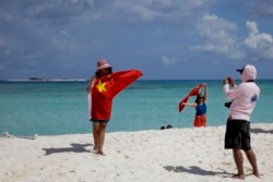 Chinese tourists take souvenir photos with the Chinese national flag as they visit Quanfu Island, one of Paracel Islands, on September 14, 2021. (Peng Peng/AP)
