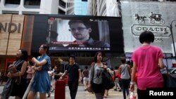 Suasana di depan pertokoan Hong Kong dengan layar televisi raksasa yang menampilkan sosok Edward Snowden, mantan pegawai kontrak Keamanan Nasional Amerika (NSA) yang dilaporkan telah meninggalkan Hong Kong, Minggu (23/6).