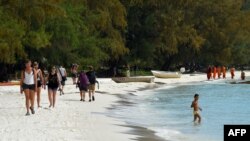 FILE - Tourists walk along a beach on Koh Rong island in Sihanoukville province on October 31, 2019.