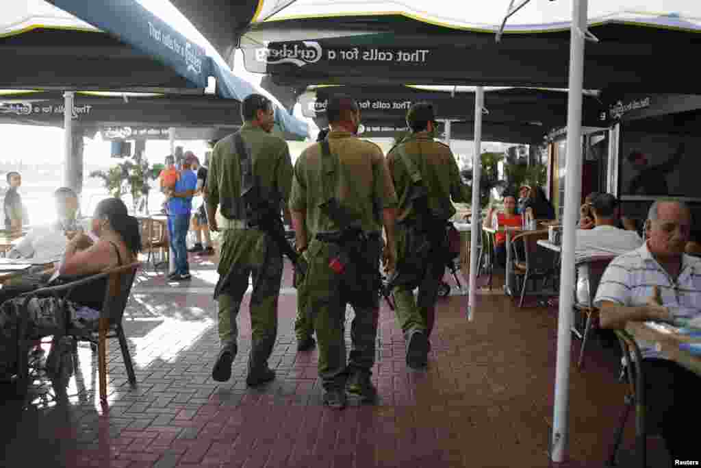Israeli reservists walk in a Marina recreation area at the southern Israeli city of Ashkelon August 11, 2014.